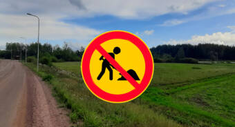 Ett fingerat trafikmärke med förbud mot grävarbeten ovanpå en obebyggd tomt.