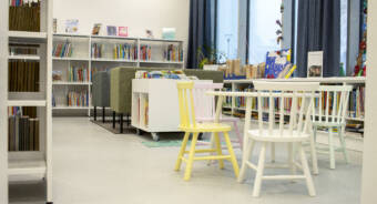 Kirjaston lasten osasto jossa on kaksi sohvaa vastakkain sekä ympyrän muotoinen lasten pöytä ja neljä tuolia.