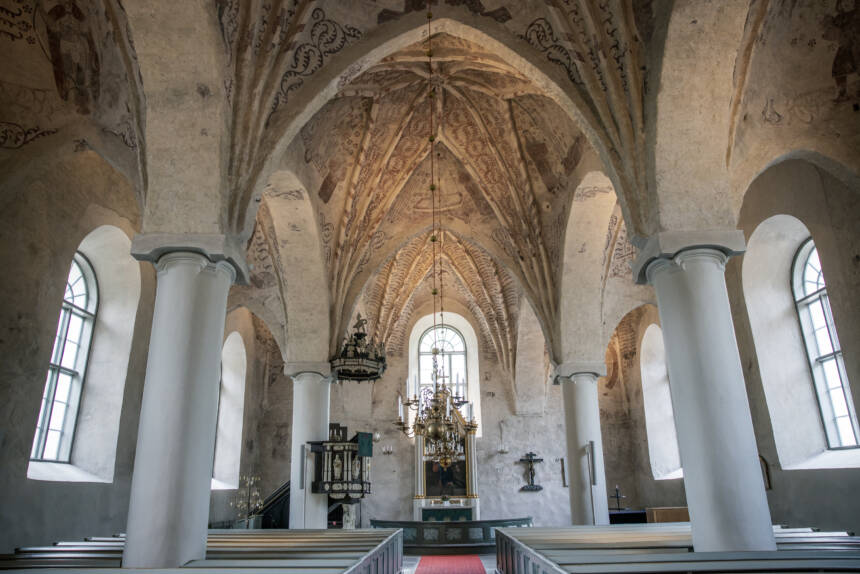 På bilden syns altaret och takmålningar inne i kyrkan.