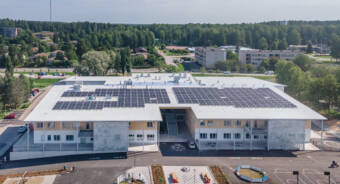 Flygbild på bilndingscampuset Sjundeå hjärta. På byggnadens tak finns solpaneler, skolgården är stor med olika lekmöjligheter.