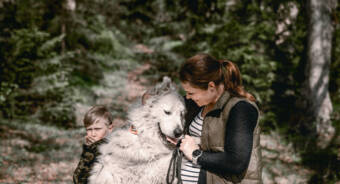 En kvinna och ett barn med sin vita hund i naturen