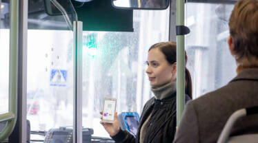 Nuori nainen näyttää lippua puhelimen näytöltä bussissa.